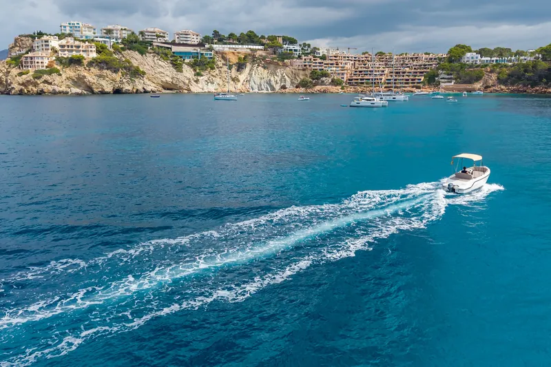 Barca dejando estela frente a una urbanización de la costa de Mallorca