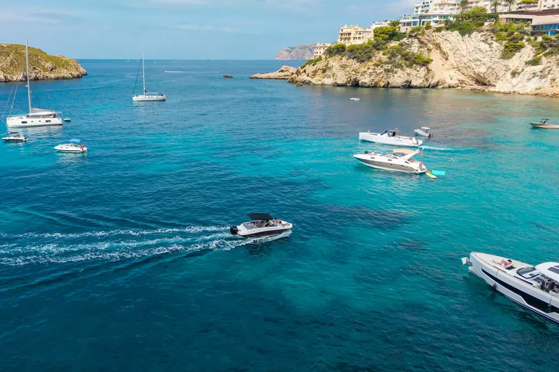 Cala con barcos fondeados y agua turquesa desde el dron