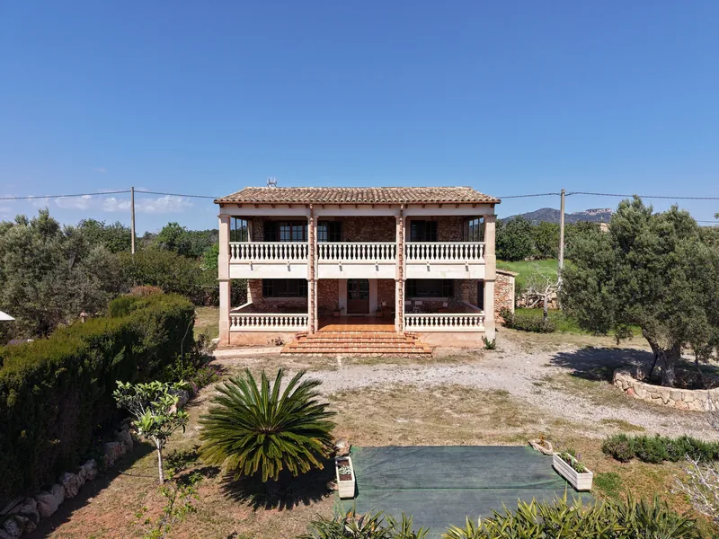 Fachada de casa de campo con porches y entorno de olivos desde el dron