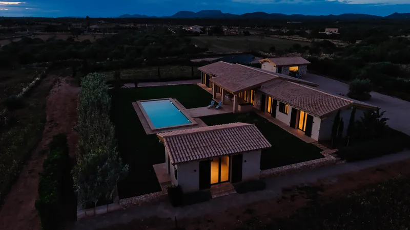Villa con la piscina iluminada de noche, fotografiada con dron