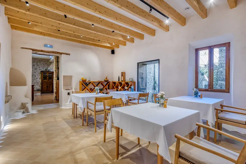 Comedor de hotel con vigas de madera y mesas vestidas de blanco