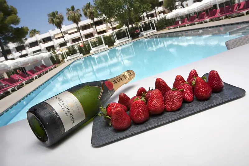 Bandeja de fresas y botella de cava junto a la piscina