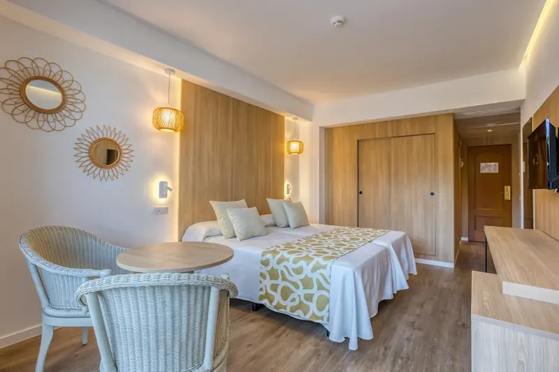 Habitación de hotel con dos camas y espejos de mimbre en forma de sol