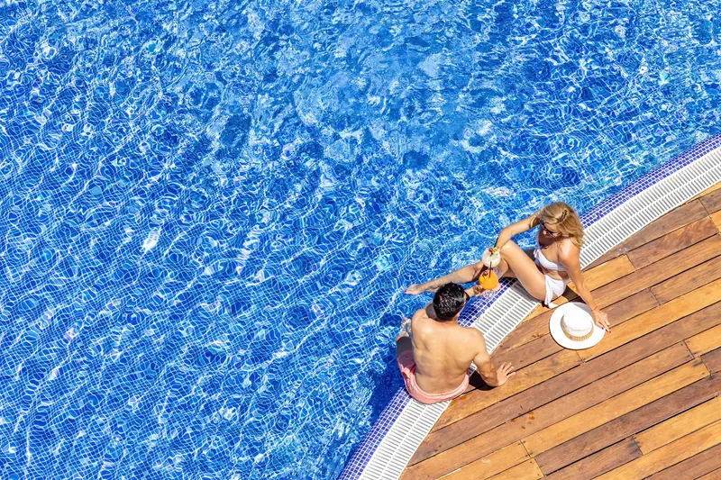 Vista cenital de una pareja descansando en el borde de la piscina