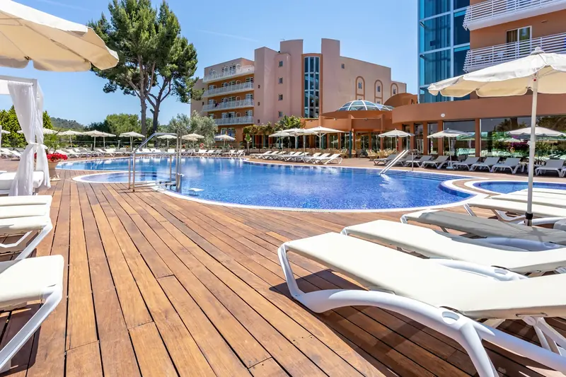 Piscina de hotel con solárium de madera y tumbonas blancas