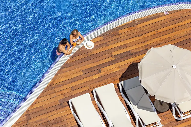 Vista cenital de la piscina con solárium de madera y tumbonas