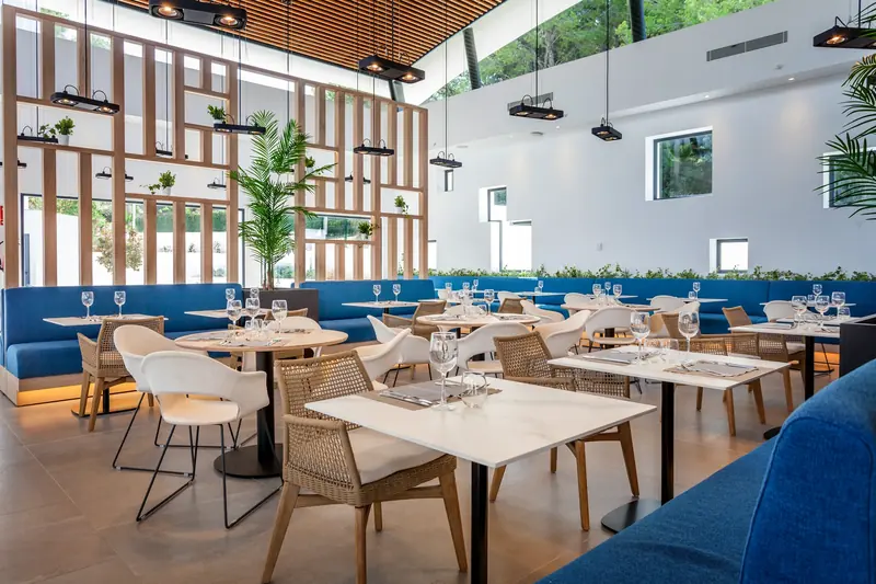 Restaurante de hotel con celosías de madera y bancos azules