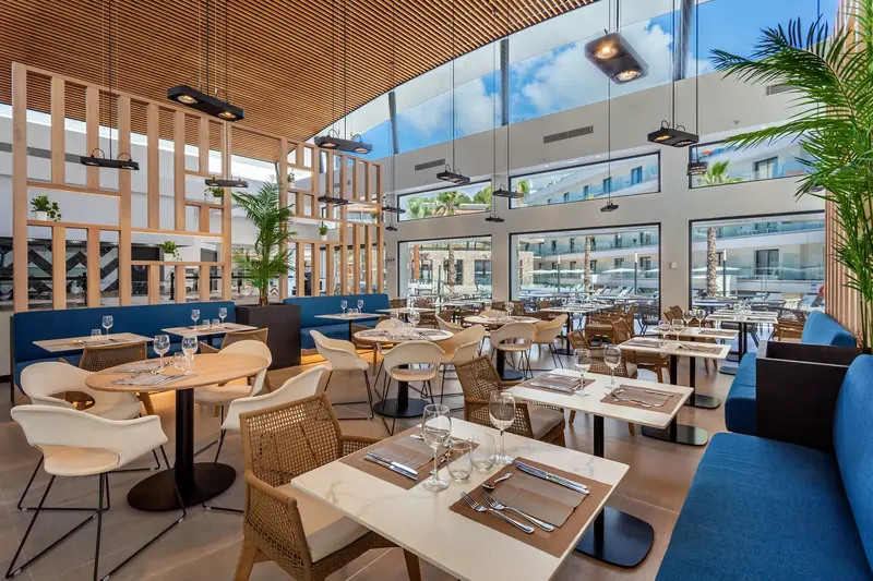 Restaurante luminoso con celosías de madera y vistas a la piscina