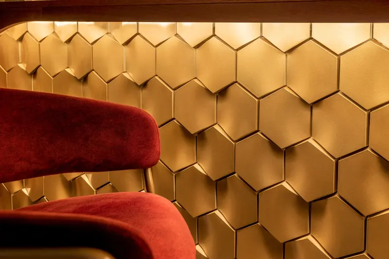 Pared de hexágonos dorados y silla de terciopelo