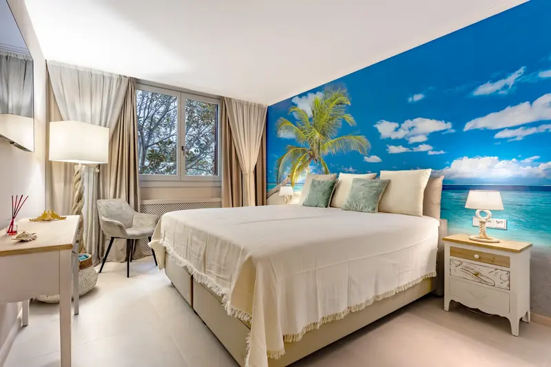 Dormitorio con mural de playa tropical en el cabecero