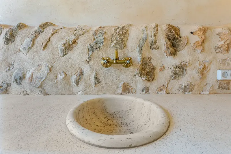 Lavabo tallado en piedra junto a una pared de piedra
