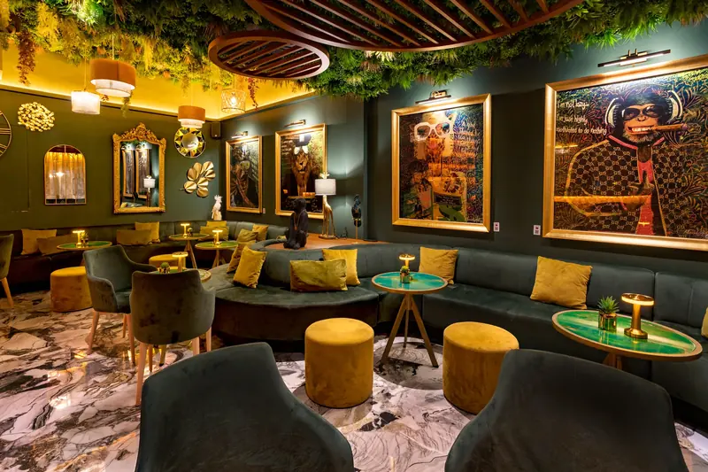 Sala lounge con sofás verdes y pufs mostaza
