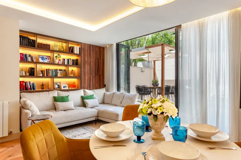 Salón comedor con librería iluminada y mesa puesta