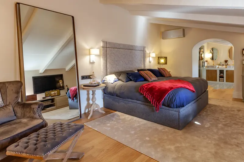 Suite con cama tapizada y gran espejo de pie