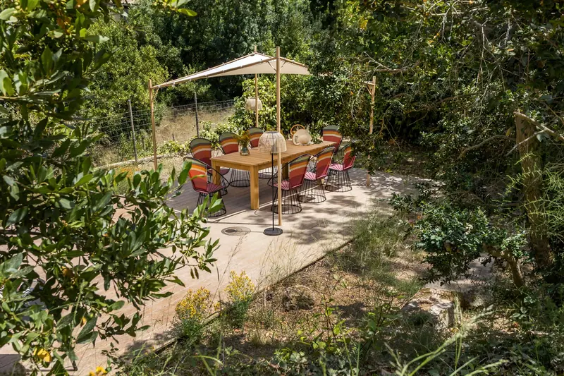 Comedor exterior bajo sombrilla en un jardín mediterráneo