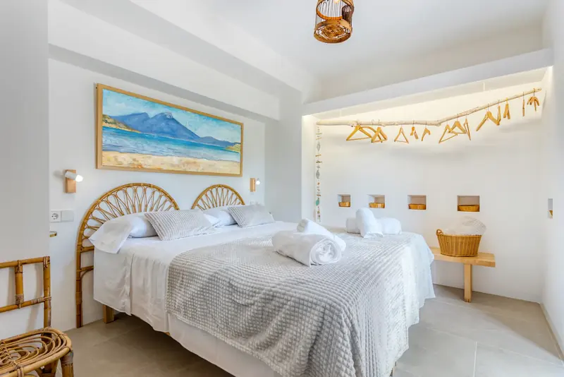 Dormitorio con cabeceros de mimbre y cuadro de paisaje