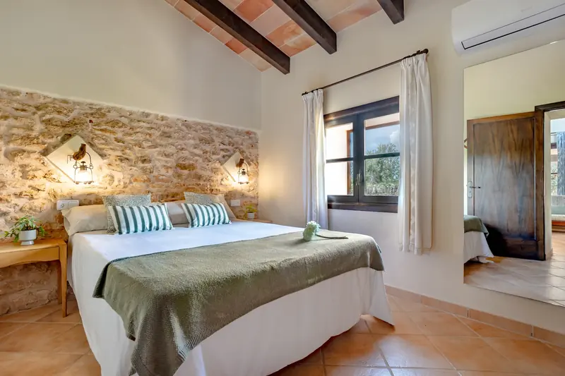 Dormitorio con pared de piedra y techo de vigas