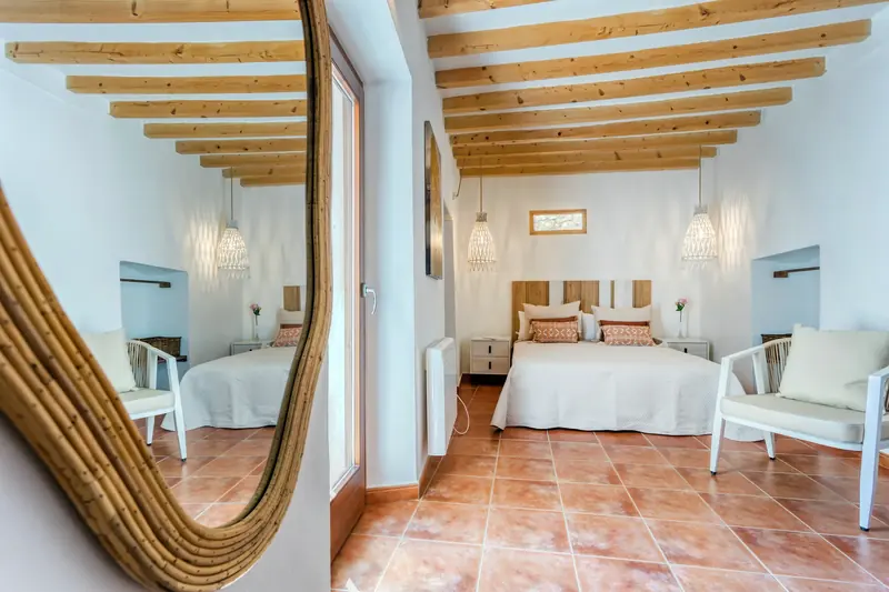 Dormitorio con vigas de madera y espejo de mimbre