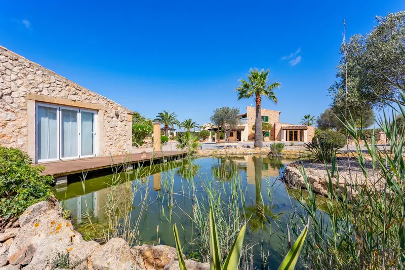 Estanque con pasarela de madera junto a casas de piedra
