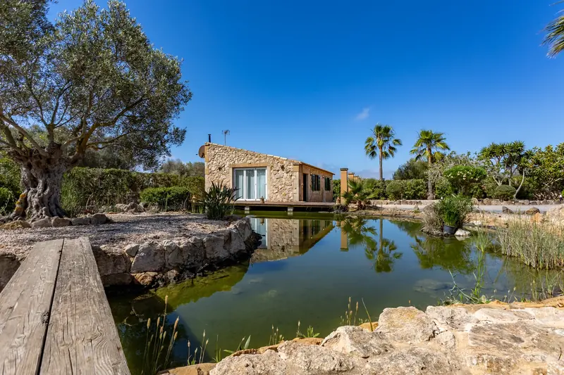 Estanque natural en una finca con casa de piedra