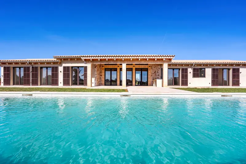 Fachada de casa de piedra frente a la piscina