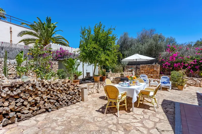 Patio con comedor exterior, leña apilada y buganvillas