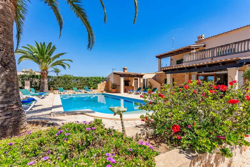Piscina de villa con palmeras y jardín en flor