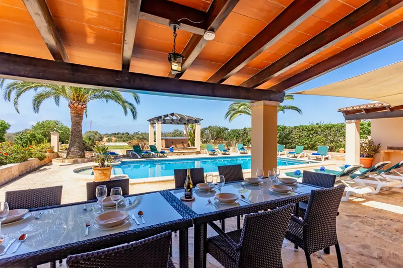 Porche con la mesa puesta frente a la piscina
