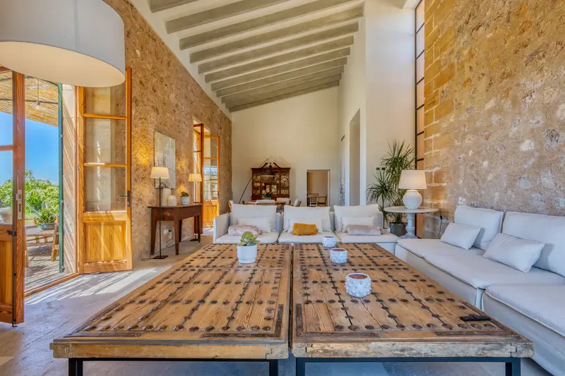 Salón de doble altura con muros de piedra y vigas