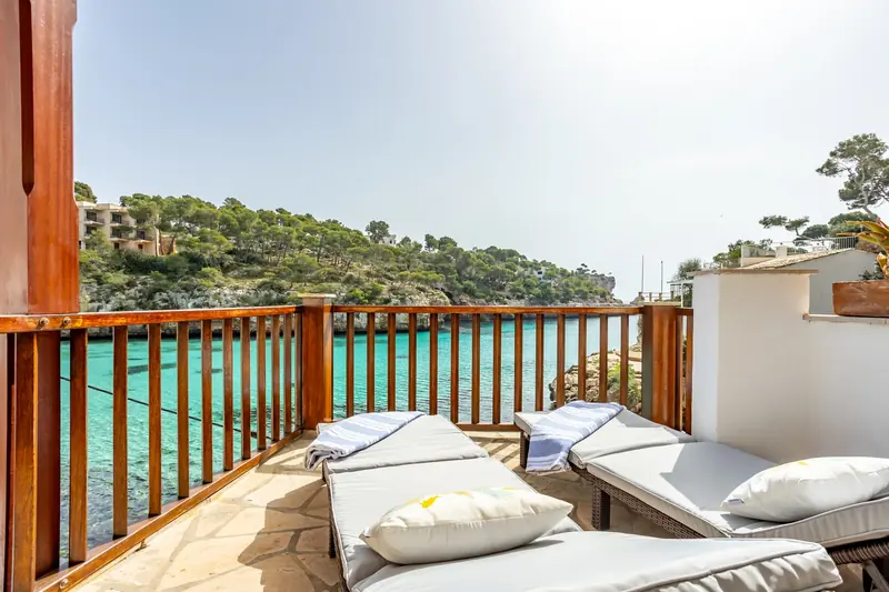 Terraza con tumbonas sobre una cala de agua turquesa
