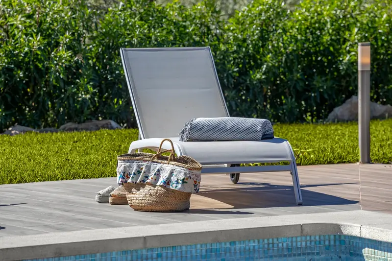 Tumbona con capazo y toallas junto a la piscina
