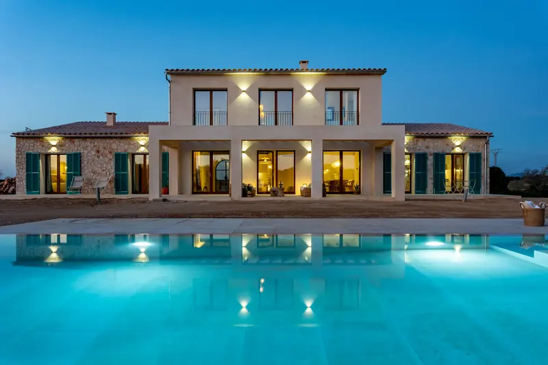 Villa de piedra con la piscina iluminada al anochecer